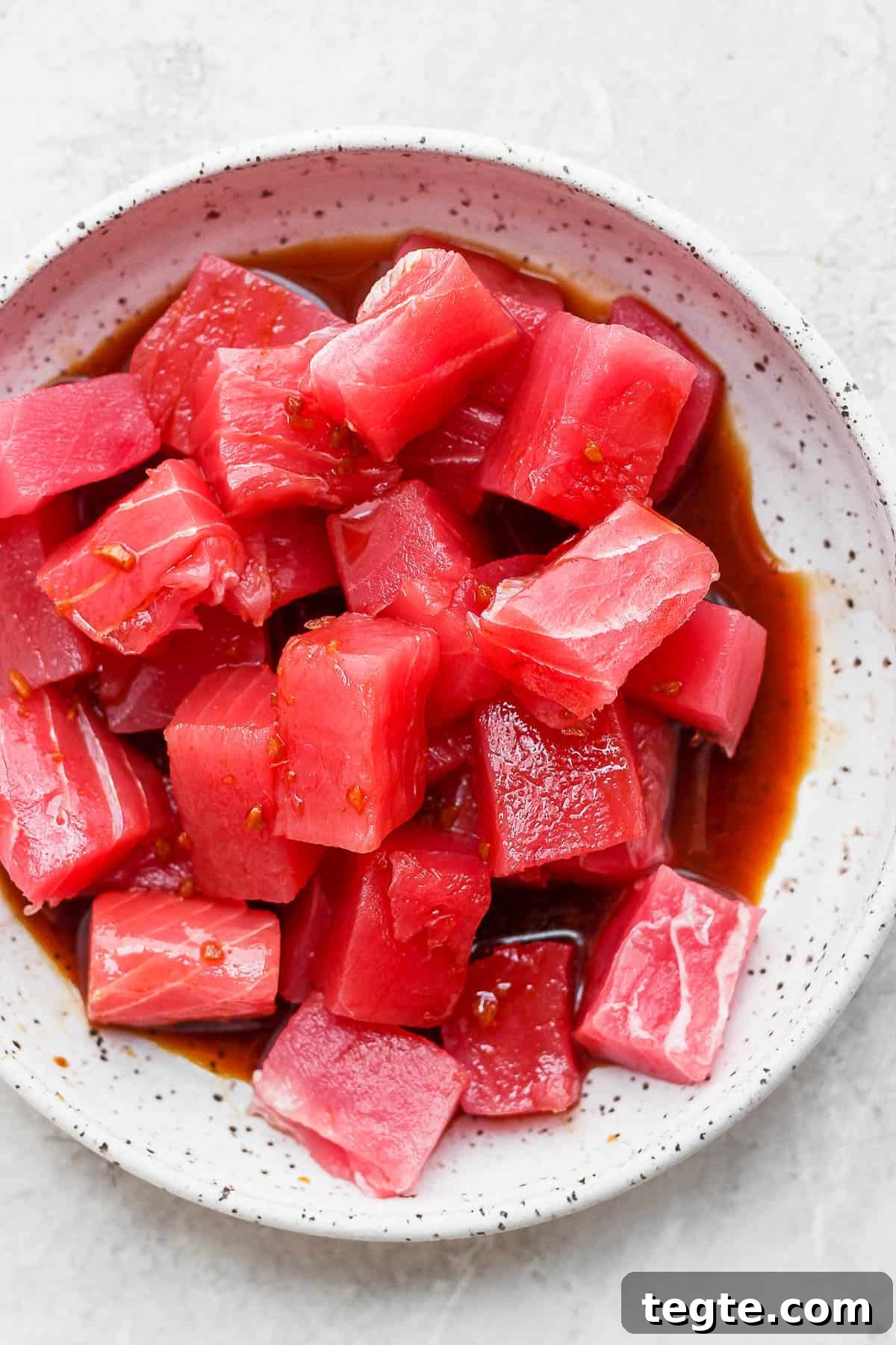 Fresh Tuna Poke Bowl Recipe: Quick Hawaiian-Style Lunch 5 Chunks of cut up raw ahi tuna marinating in poke sauce.