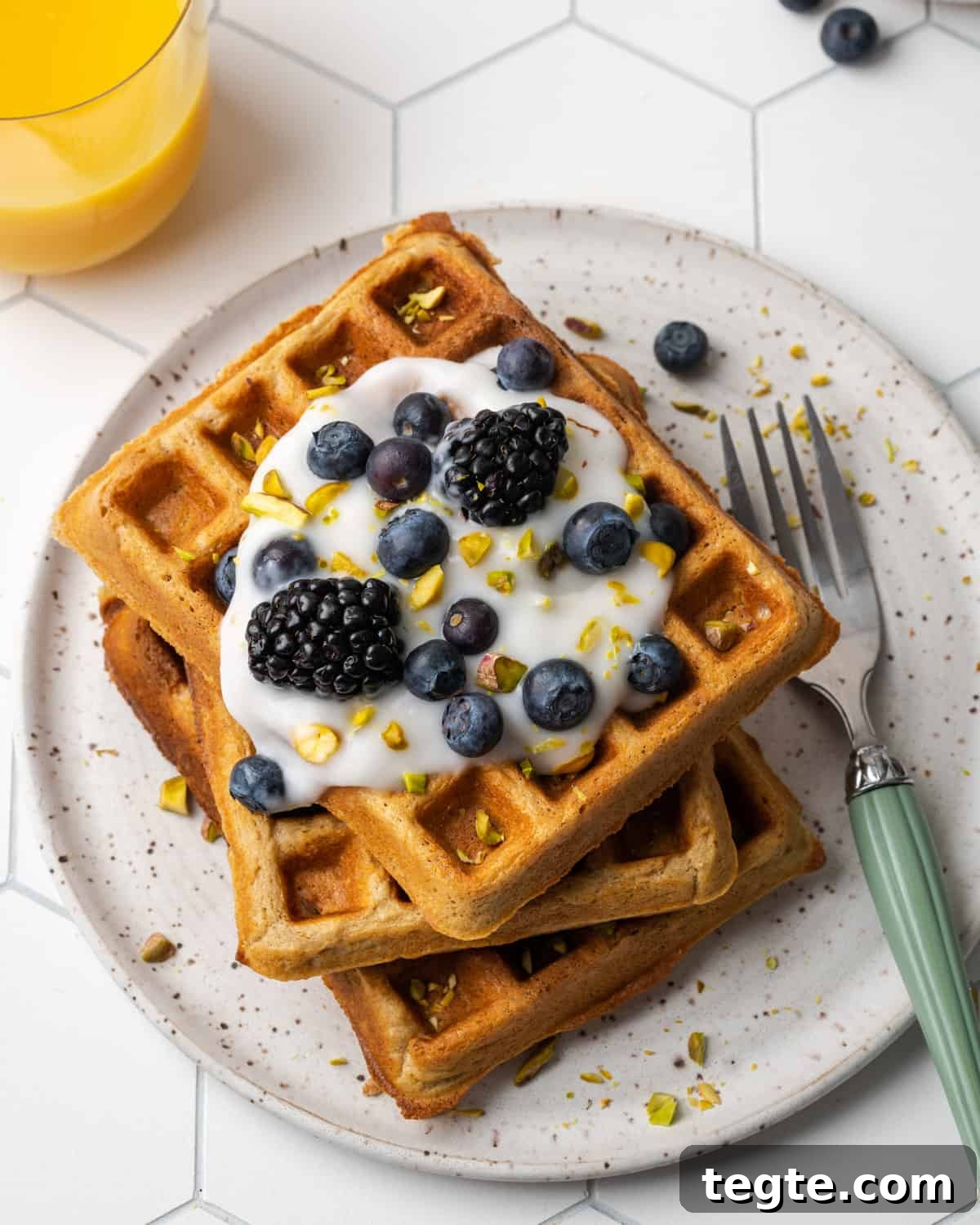 Crispy Oat Flour Waffles Recipe - Fluffy & Gluten-Free Option 2 A stack of three golden oat flour waffles topped with dairy free yogurt, blueberries, blackberries and chopped pistachios.