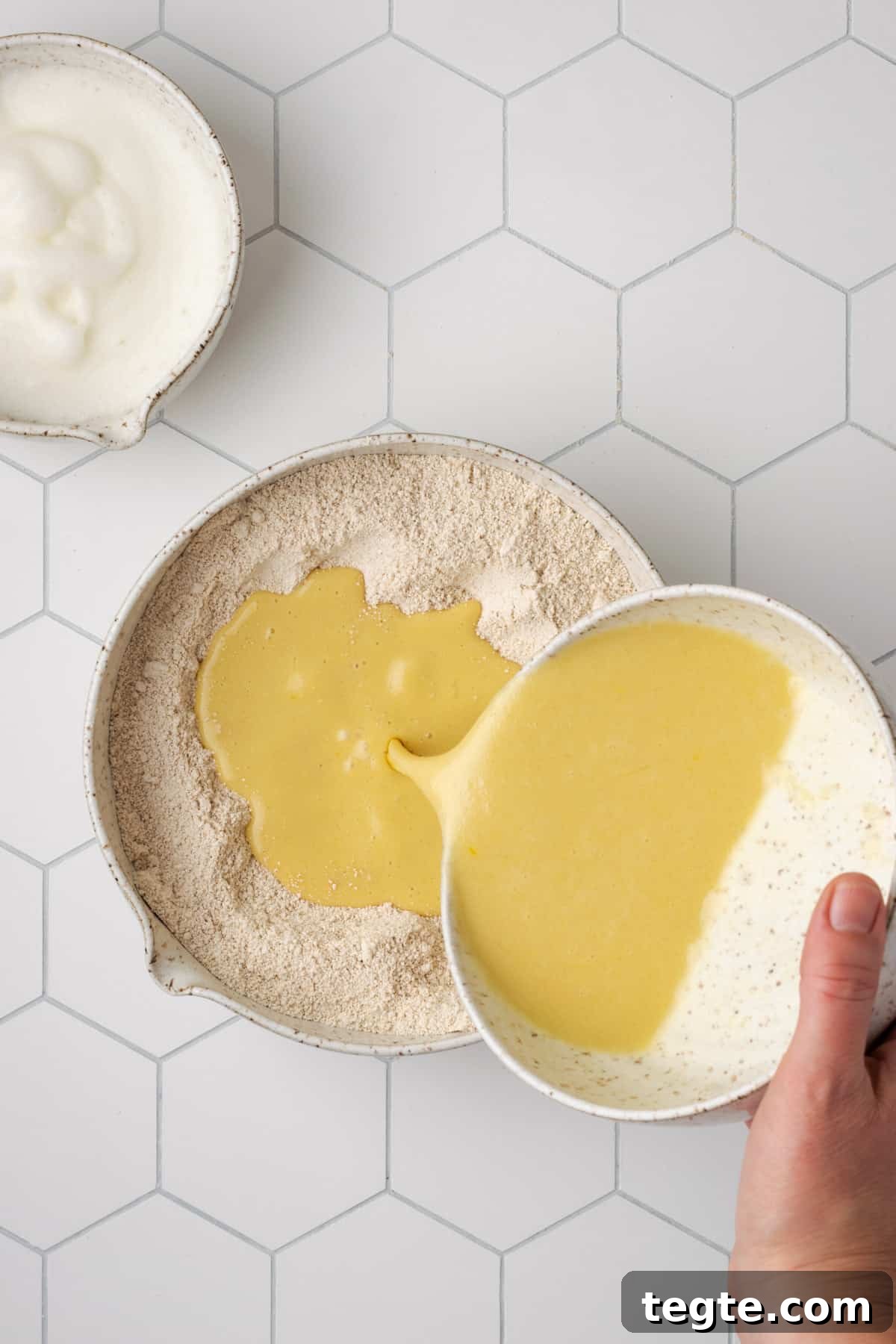 Crispy Oat Flour Waffles Recipe - Fluffy & Gluten-Free Option 11 Liquid ingredients being poured into the large bowl with the flour.