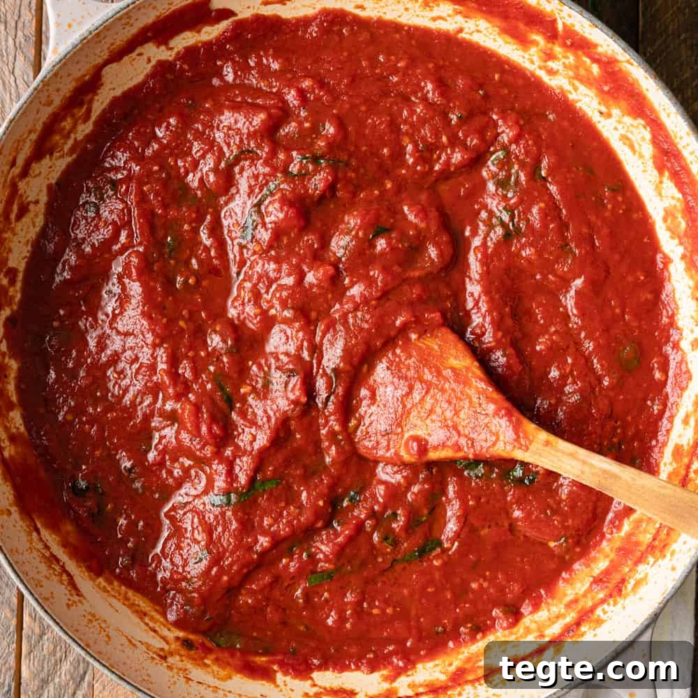 Homemade Marinara Sauce for Spaghetti (Meatless) 2 overhead: stirring marinara sauce with a wooden spoon as it cooks in a large skillet