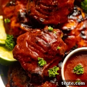 Oven-Baked BBQ Chicken Thighs with Crispy Skin and Sticky Glaze 9 baked chicken thighs covered in bbq sauce on a silver plate.
