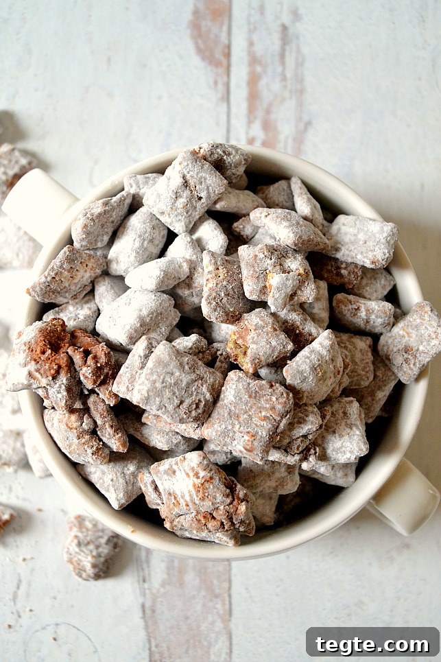 Ultimate Muddy Buddies Recipe — Perfect Chocolate-Peanut Rice Cereal Snack 3 White bowl filled with muddy buddies on a white wood board