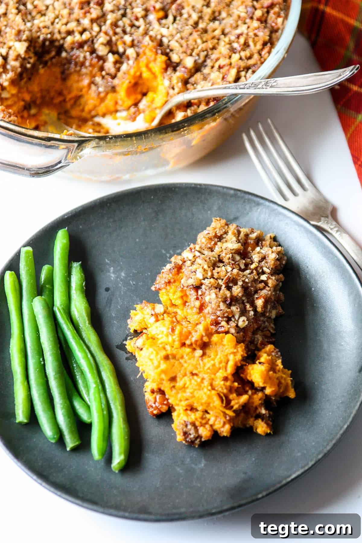A serving of sweet potato crunch with green beans on a black plate.