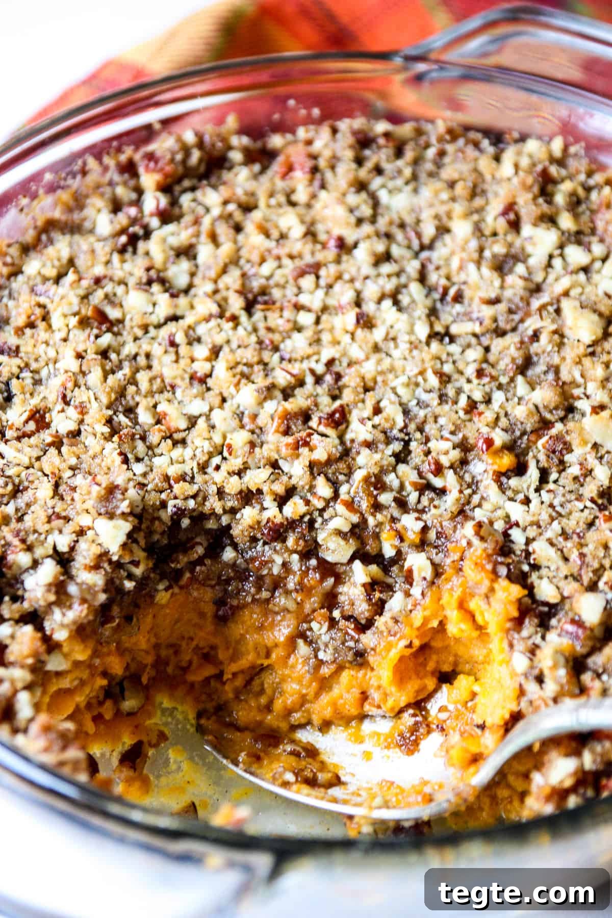 A close up of a serving spoon in a dish of sweet potato crunch casserole.