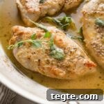 Oregano Roasted Chicken with Lemon and Garlic 7 Close up of a pan-fried chicken breast seasoned with white wine sauce and oregano.