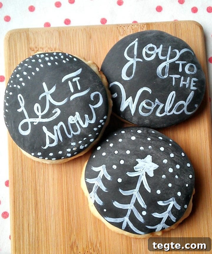 sugar cookies on a wooden board that look like chalkboard with messages that read let it snow and joy to the world