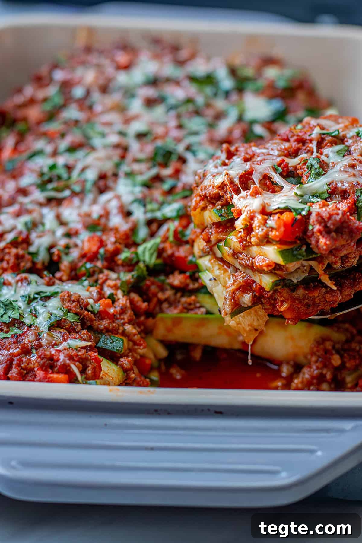 Zucchini Lasagna with Rich Bolognese Meat Sauce 2 A spatula scooping out a slice of zucchini lasagna with ground meat and tomato sauce.