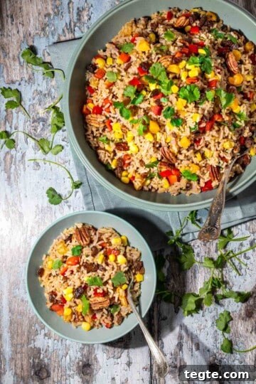 A large bowl with brown rice salad with a smaller bowl next to it.