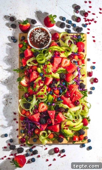 Rainbow salad on a wooden board and a white background.