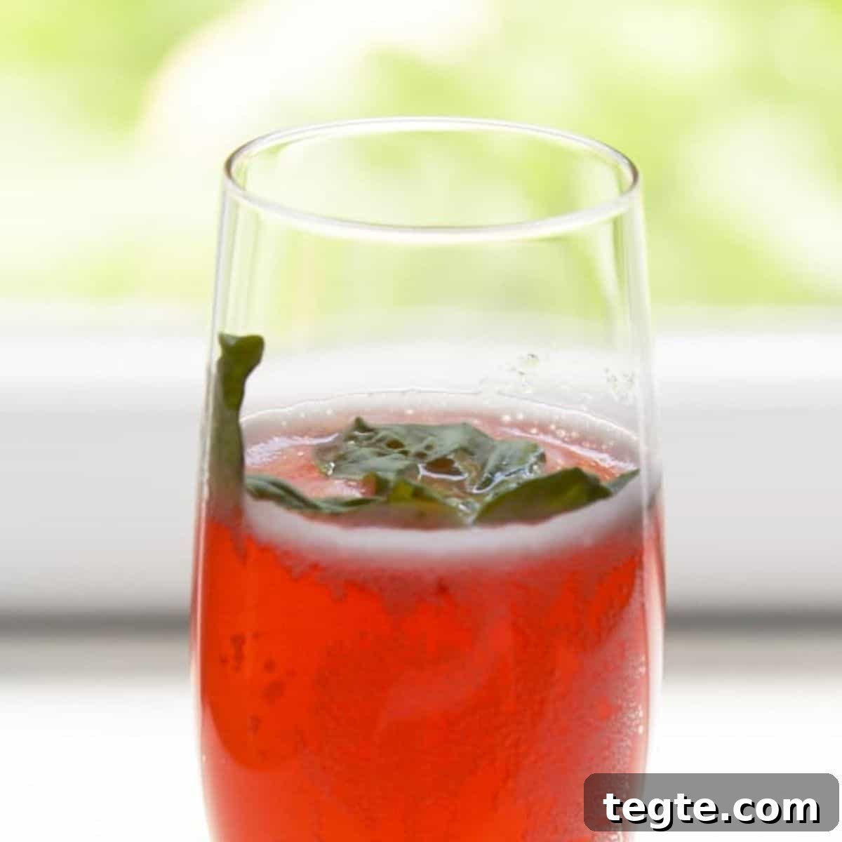 A strawberry basil Prosecco cocktail garnished with fresh basil leaves.