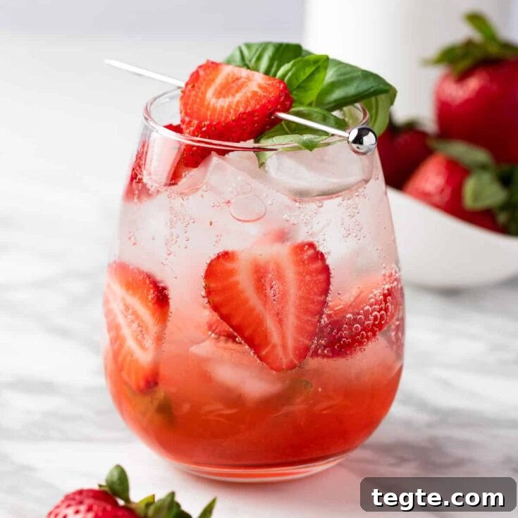 A strawberry basil mocktail garnished with fresh basil leaves and strawberry slices.