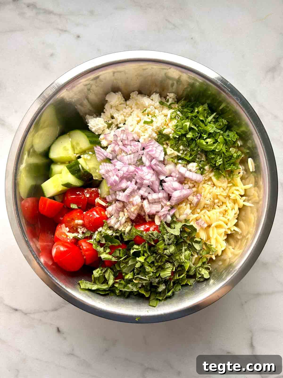 Mediterranean Orzo Salad with Lemon Herb Vinaigrette 6 components in bowl unmixed.