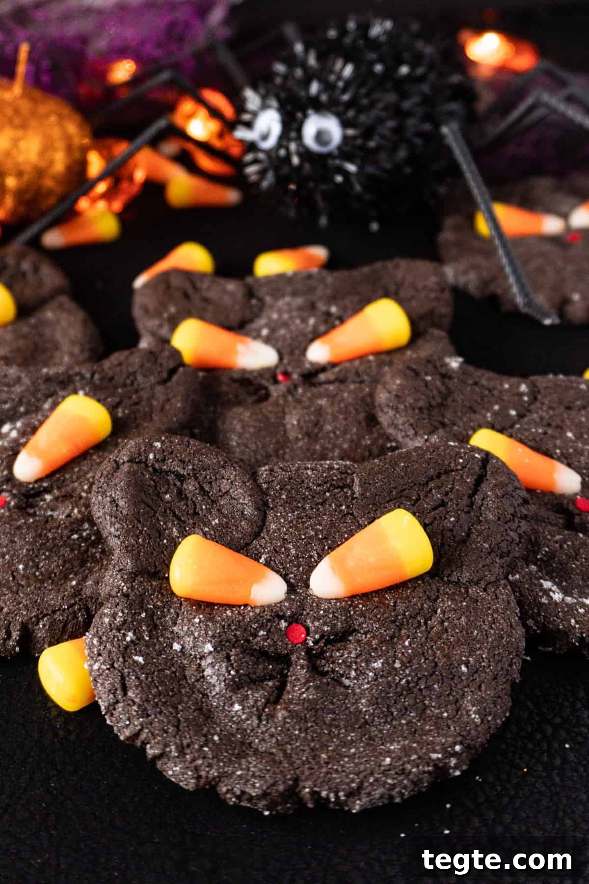 Black Cat Cookie Recipe: Soft Chocolate Drops for Halloween 2 Black Cat Cookies with candy corn eyes stacked on another with a fake spider in the background.