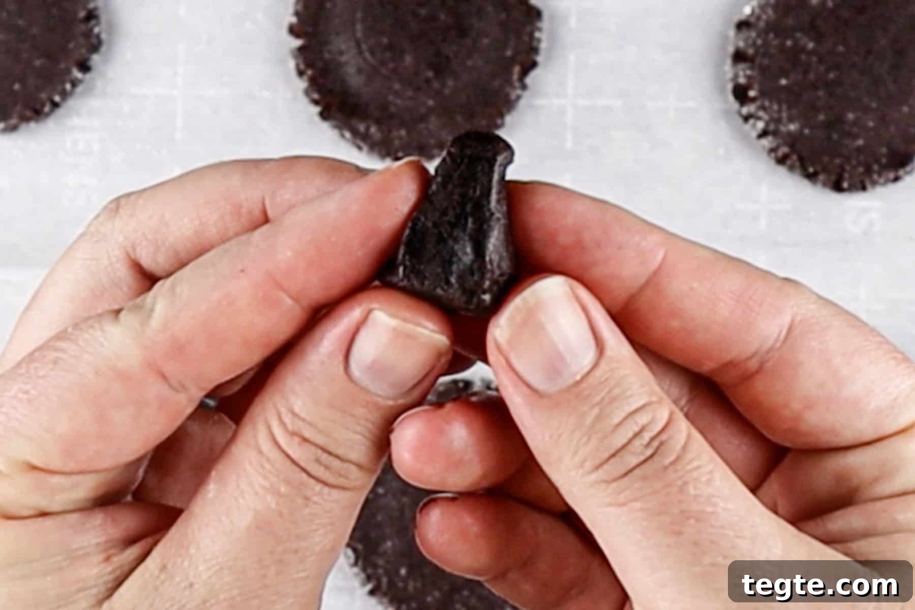 Black Cat Cookie Recipe: Soft Chocolate Drops for Halloween 9 forming a triangular ear for the cat cookie out of cookie dough.