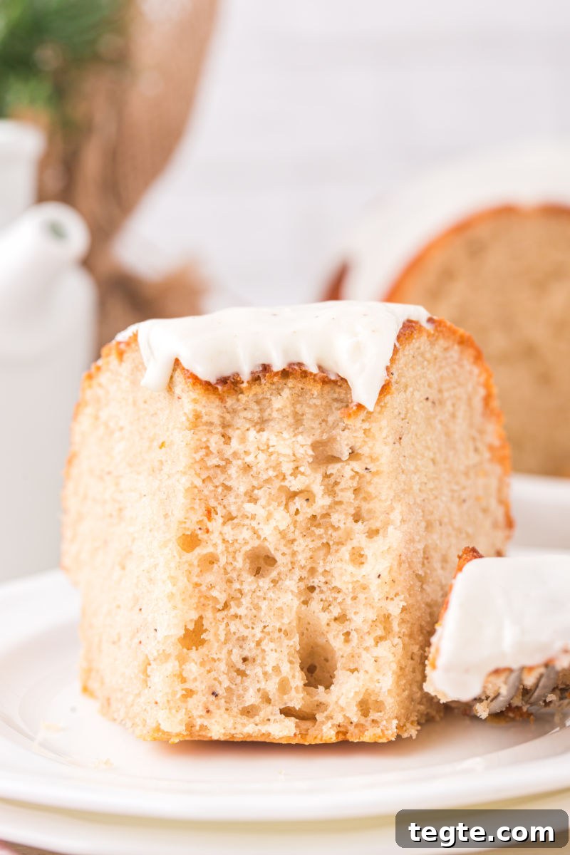 bite of eggnog bundt cake on a fork next to the slice on a dessert plate