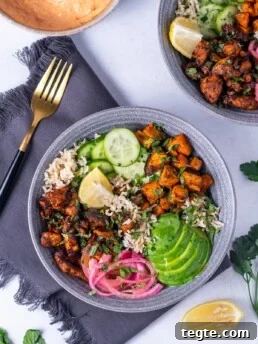 bowl with honey harissa chicken, avocado, sweet potatoes, pickled red onions, cucumber and brown rice