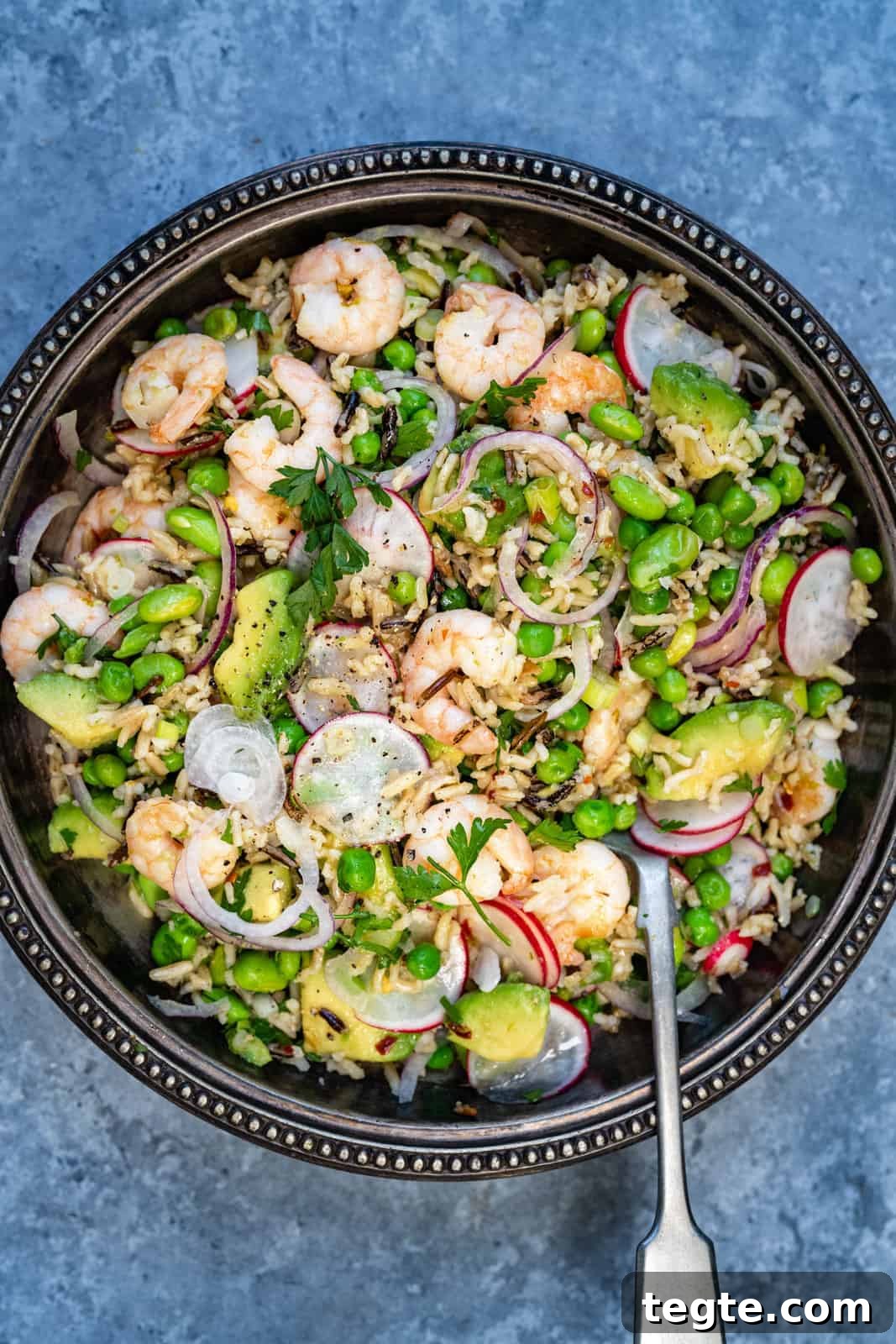 Close up on a bowl of prawn salad with avocado, peas and rice