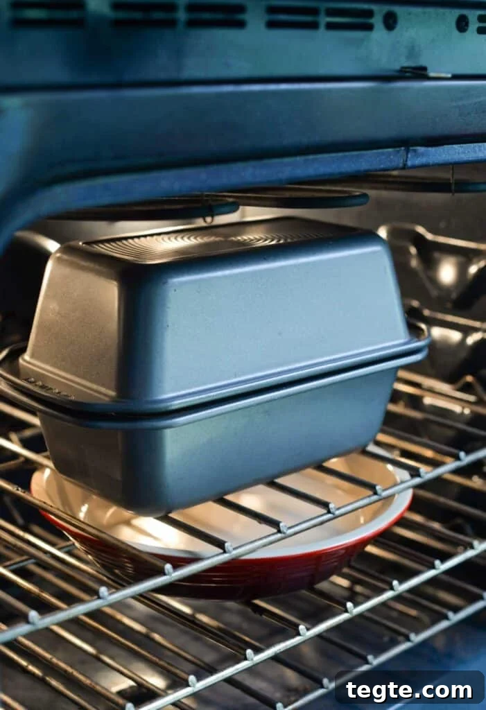 Two loaf pans are tipped to form an enclosed pan in an oven.