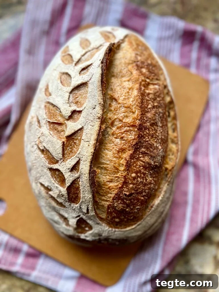An oval shaped loaf of artisan bread sits on a cutting board.