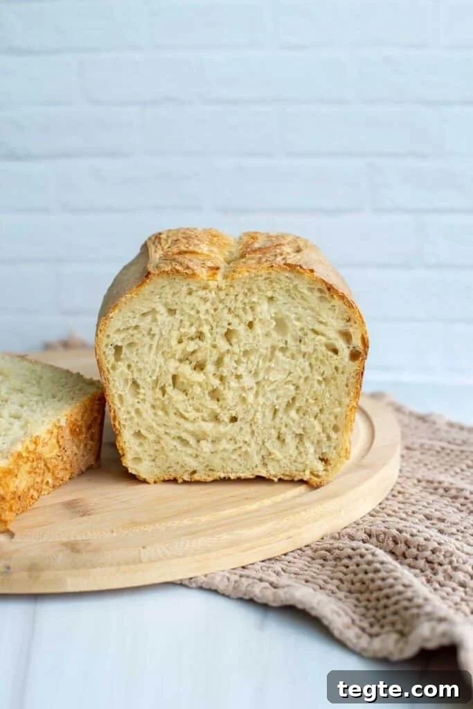 A loaf of sourdough brad has been sliced and sits on a cutting board.