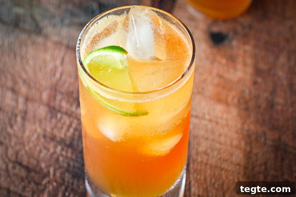 Horizontal photo of A tall glass with the cocktail with lime wedges