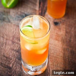 square view of a tall glass with the cocktail in it along with a lime for garnish