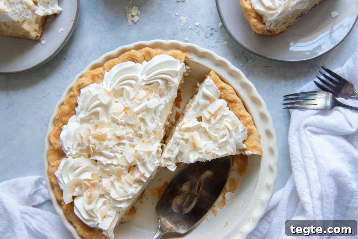overhead view of coconut cream pie with slices missing in a pie pan.