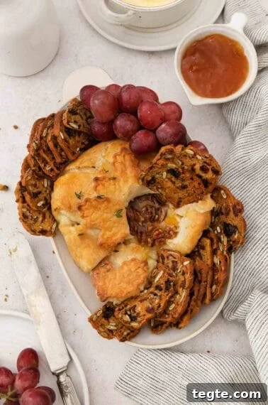 Gluten-free baked Brie on a platter with gluten-free crackers and grapes.