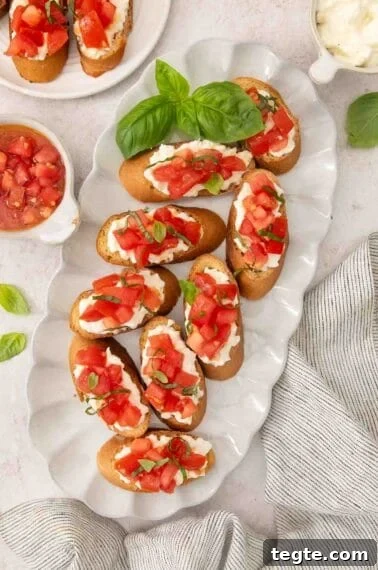 Gluten-free bruschetta laid on a platter, with basil leaves garnishing the plate and scattered on the table.