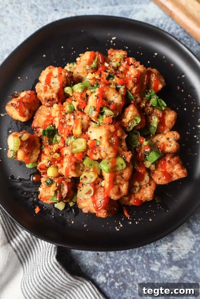 Crispy Salt-and-Pepper Tofu Made in the Air Fryer 2 black plate with salt and pepper tofu topped with green onion, red chili pepper, and garlic