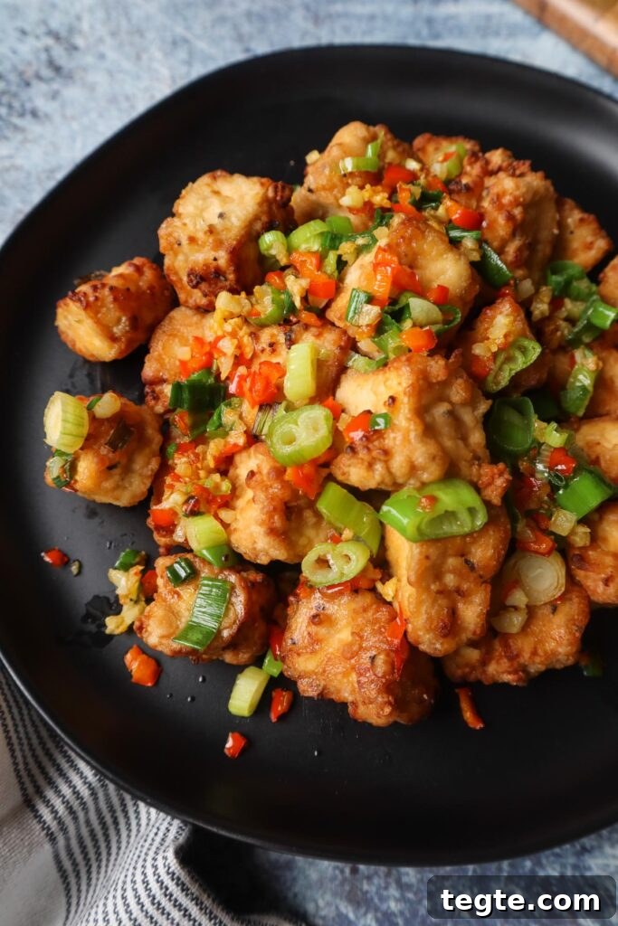Crispy Salt-and-Pepper Tofu Made in the Air Fryer 3 black plate with salt and pepper tofu topped with green onion, red chili pepper, and garlic