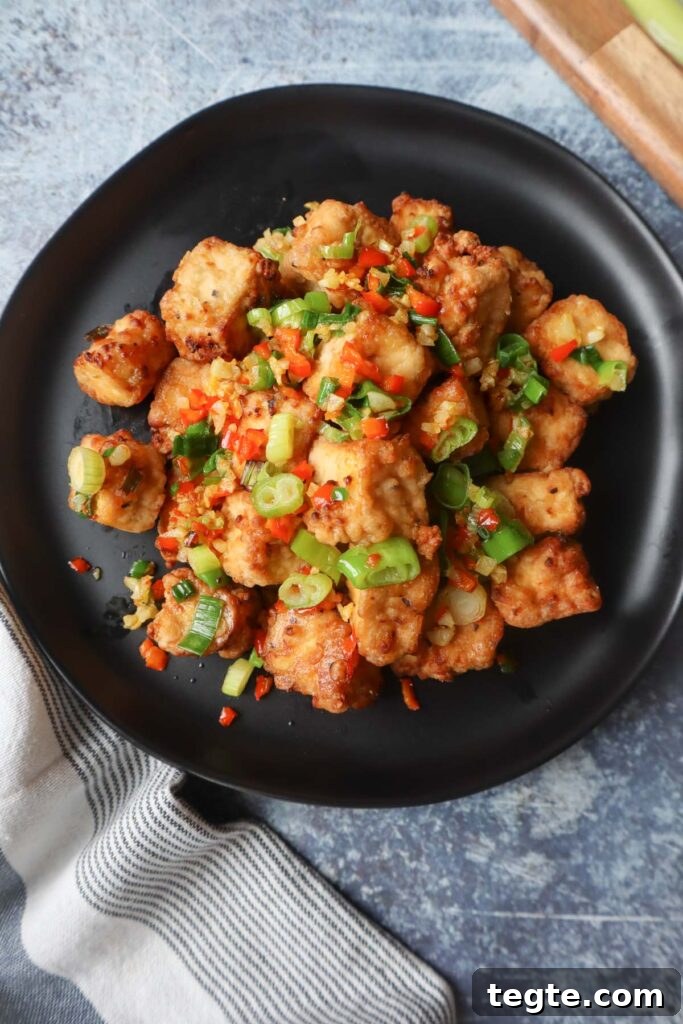 Crispy Salt-and-Pepper Tofu Made in the Air Fryer 6 black plate with salt and pepper tofu topped with green onion, red chili pepper, and garlic