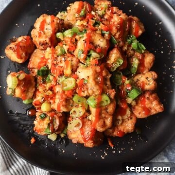 Crispy Salt-and-Pepper Tofu Made in the Air Fryer 8 black plate with salt and pepper tofu topped with green onion, red chili pepper, and garlic