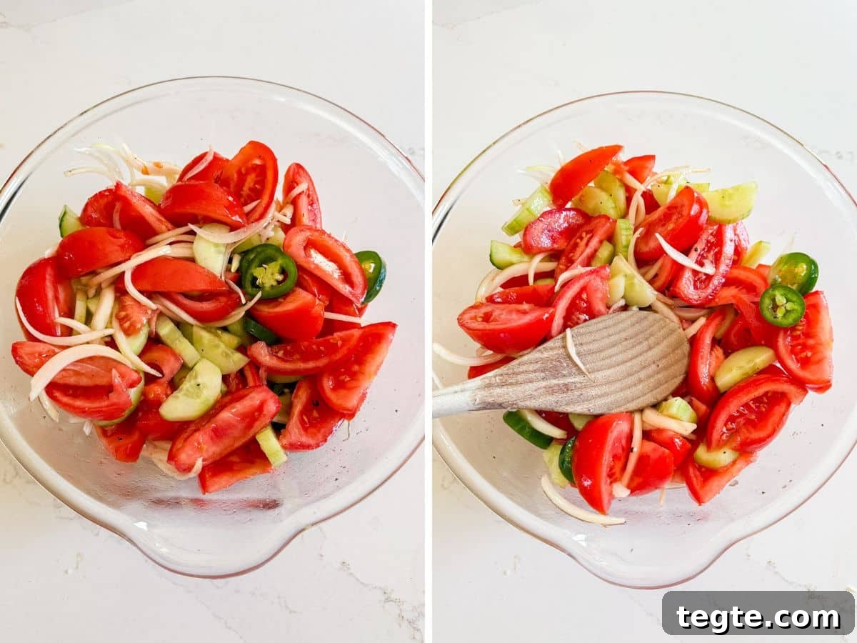 The tomato salad dressed and mixed together and then a spoon pushing down the salad once it's been chilling.