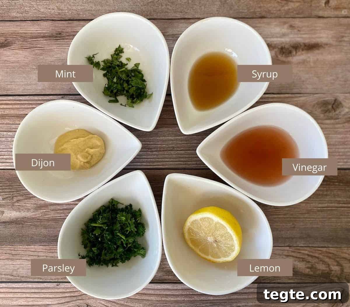 Dressing Ingredients in bowl on the counter: Mint, maple syrup, vinegar, lemon, parsley, dijon mustard and mint