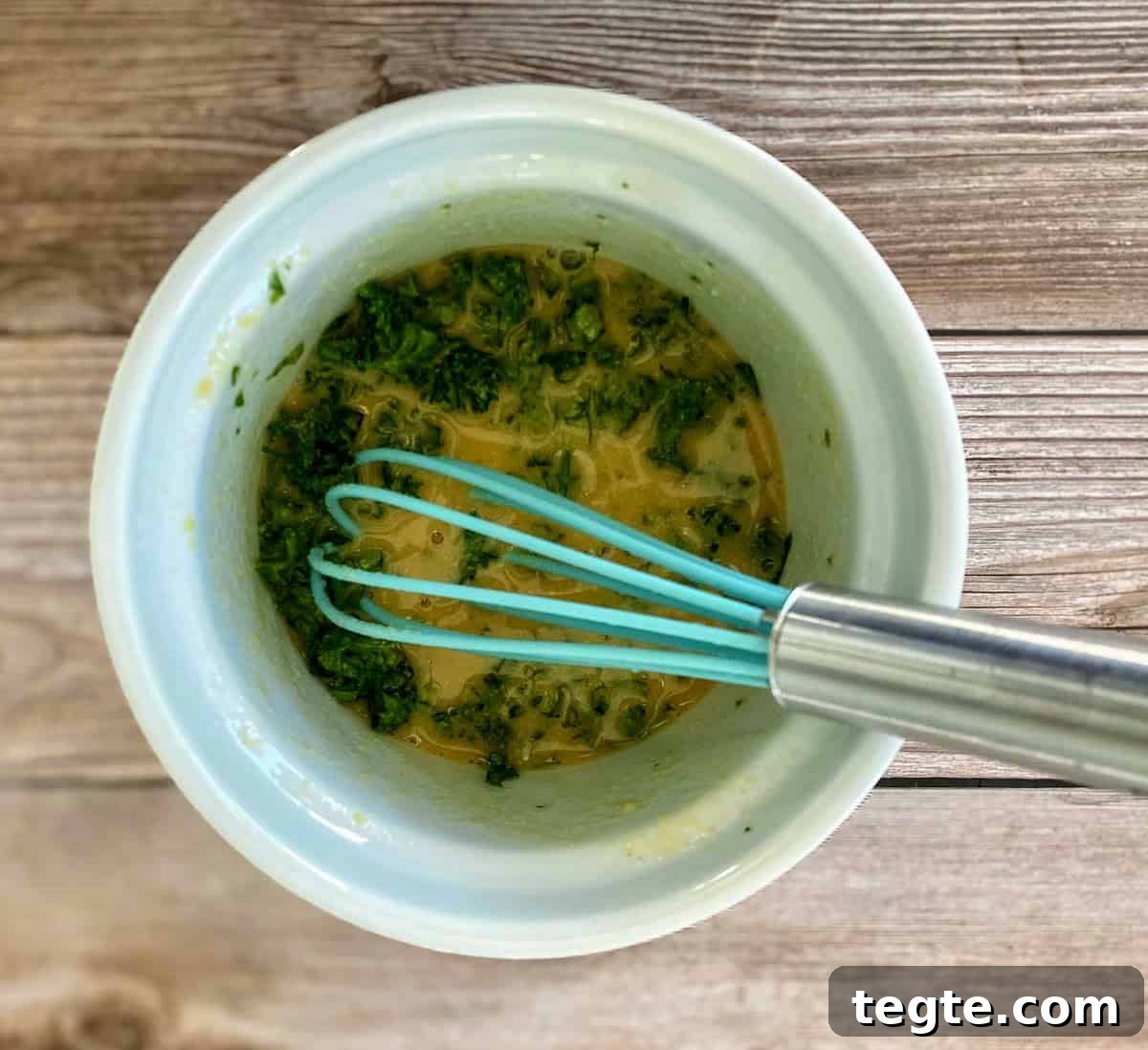 Whisking the dressing ingredients together in a bowl on the counter