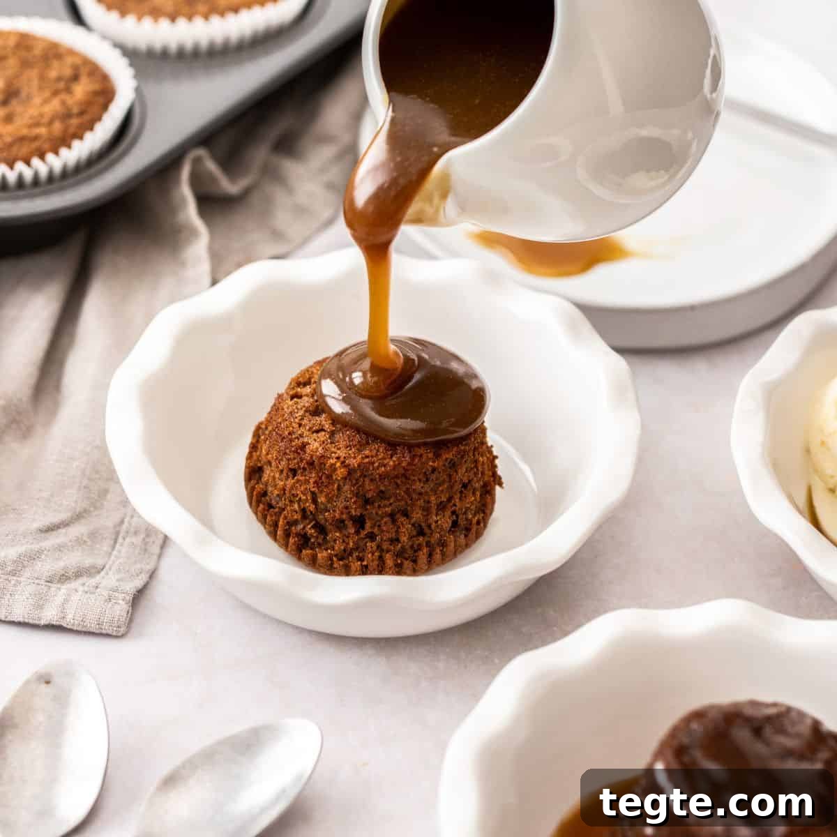 A pudding in a small dish, with some toffee sauce being poured over it.