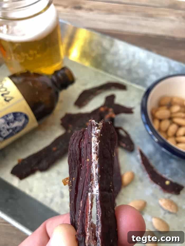 Drunken Spiced Venison Jerky Recipe 12 Deer jerky bent in half with beer and peanuts in dish in background