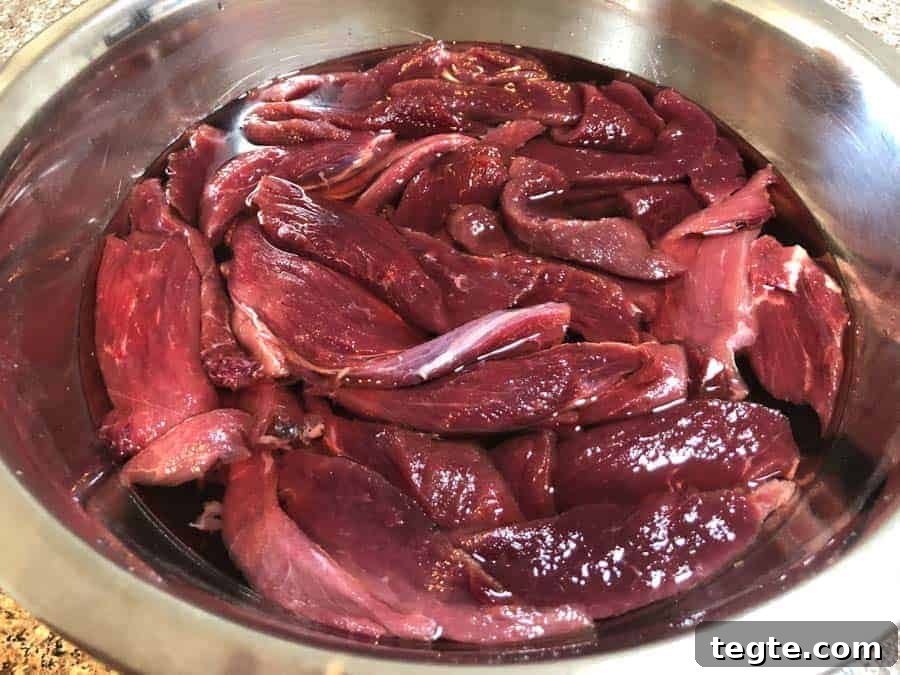 Drunken Spiced Venison Jerky Recipe 5 venison strips soaking in water and vinegar in bowl