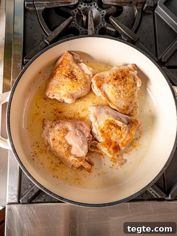 Chicken thighs browning in a pan.