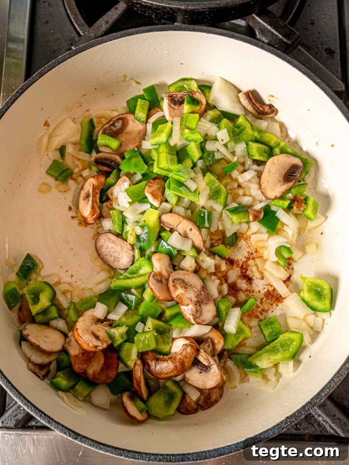 Onion, pepper and mushrooms cooking on the stove.