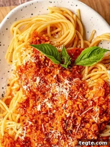 Chicken bolognese on top of spaghetti.