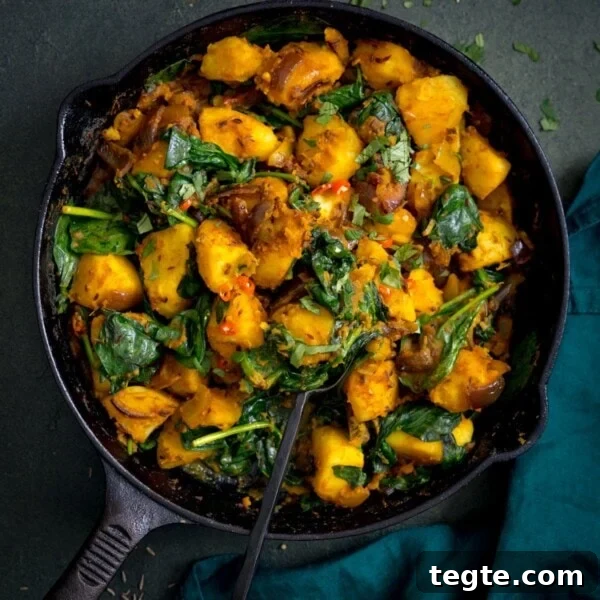 saag aloo in a black pan on a dark background