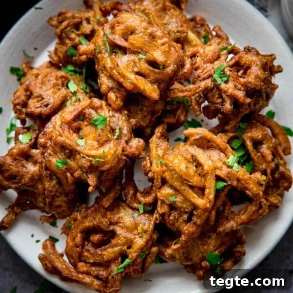 Onion bhajis on a white plate, sprinkled with coriander.