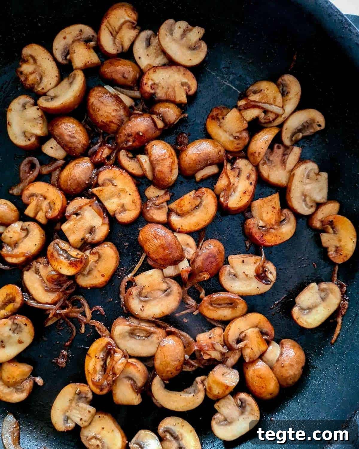 Rich and Velvety Mushroom Sauce Recipe for Pasta and Steak 5 Close up of caramelised mushroom slices and onions in a black pan