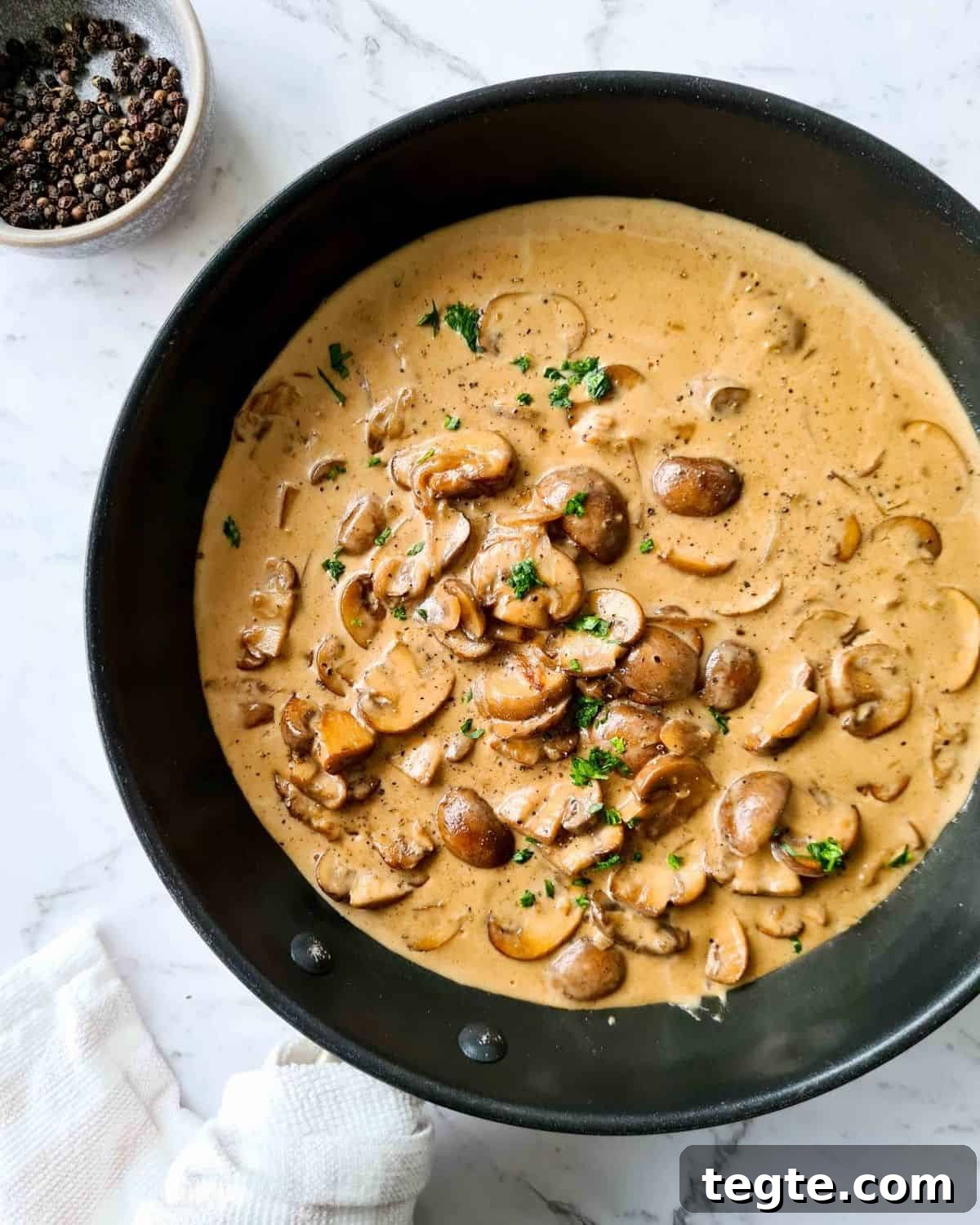 Rich and Velvety Mushroom Sauce Recipe for Pasta and Steak 7 Overhead, zoomed out view of mushrooms in creamy sauce in a black pan, ready to serve