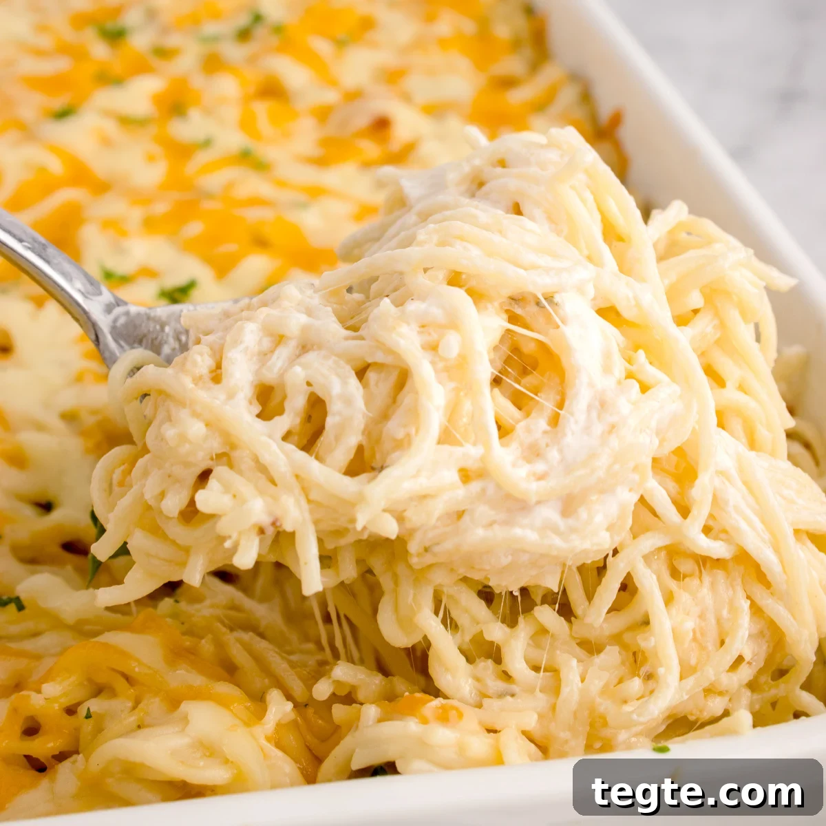 Chicken Tetrazzini in a pan with a spoonful being lifted out 