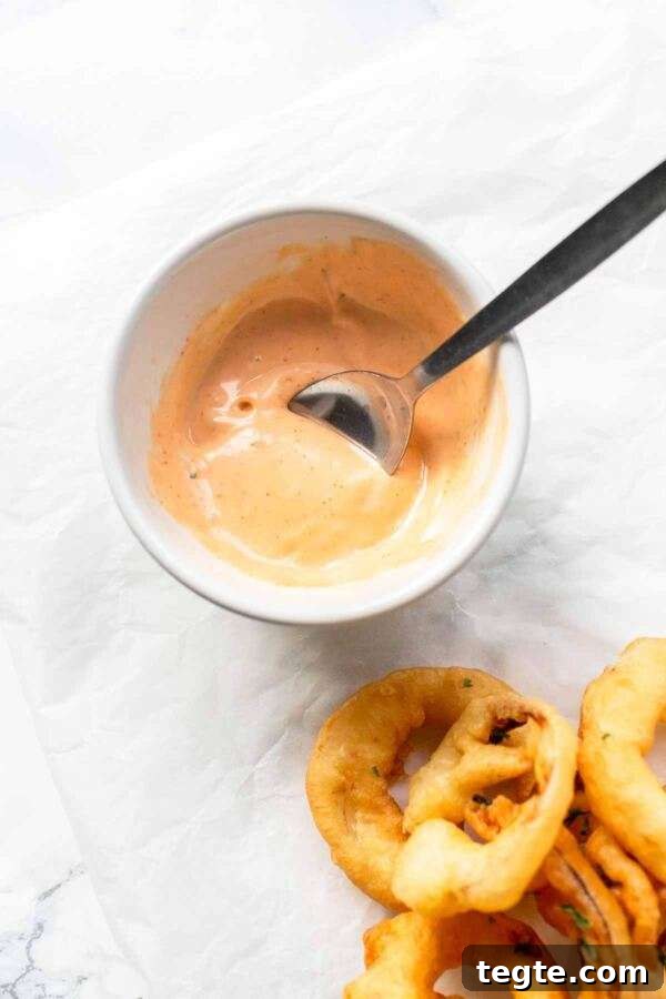 Creamy Spicy Mayo Recipe: Quick Homemade Sriracha Aioli 5 Spicy mayonnaise in a white bowl with a spoon. A tasty dip to serve with crispy onion rings.