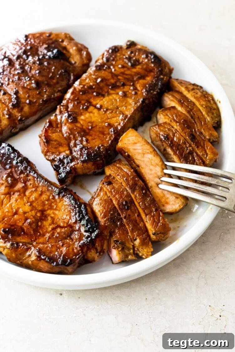 Perfectly Seared Pork Chops on a Blackstone Griddle 2 Grilled pork chops on a white plate with a fork