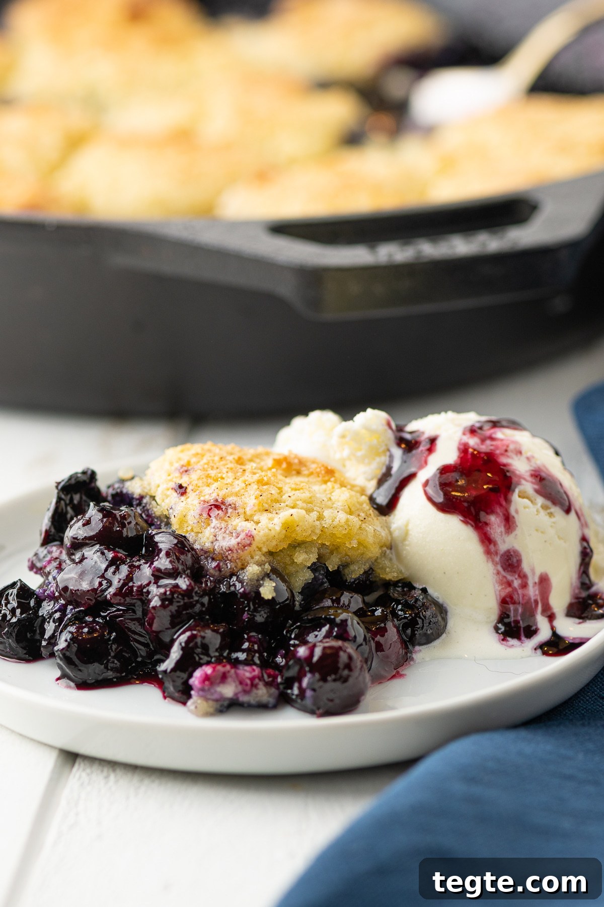 Low-Carb Blueberry Cobbler (Gluten-Free, Sticky Sweet) 3 A plate of blueberry cobbler with a scoop of ice cream drizzled with blueberry syrup